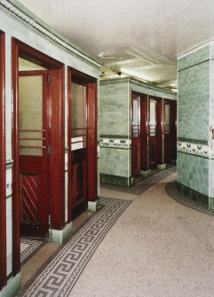 Interior. View of the two blocks of three cubicles, a further pair of cubicles being located beyond (out of picture).  All the original water closets and cisterns appear to have been removed, but most cubicles retain the green tilework.
