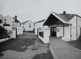 Bowmore Distillery
View of main entrance to distillery from NE, showing the adjacent indoor Bowmore Swimming Pool (right), which is heated using waste heat from the distillery