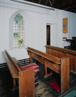 Interior. Vestry door, boarded walls, pews and window