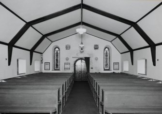 Interior. View from E showing nave, entrance and roll topped pew ends