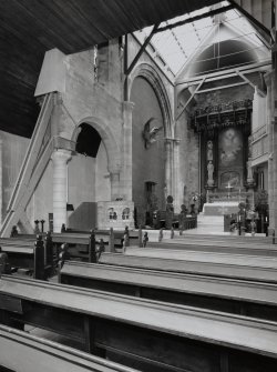 Interior. View of original part of church supported by beams from pews