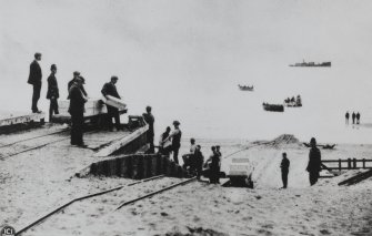 Copy of historic photograph showing loading of explosives on the wharf.