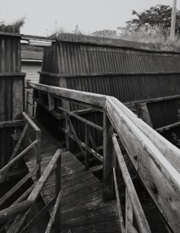 Exterior view from S at upper level of AC2 (NS 2876 3983), showing gangway and lead-lined trough approaching building through gap in reinforced baffle wall (Chilworth Mound)