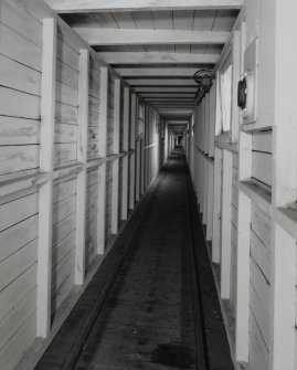 Interior view of covered gangway connecting AC2 (Nitroglycerine separation and storage house, NS 2868 3991) with Nitrocellulose/ Nitroglycerine Mixing House (PZ1, NS 2885 3984) also showing wooden guide rails for NG bogeys