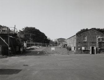 General view from NE up Nitroglycerine [NG] Hill No.2, with acid storage tanks (AJ3, left, NS 2871 3990) and Glycerine Storage building AJ2 (right, NS 2868 3991). Brick building halfway up slope is Light Sodium Carbonate building (AJ5) used to neutralise NG