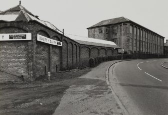 General view from NNE of single-storeyed sheds (foreground) and multi-storeyed mill (background), photographed 23 April 1992