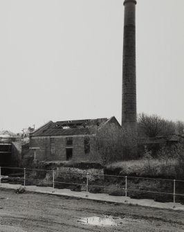 View from NW of chimney and possible former boilerhouse to S of works, on opposite (S) side of River Garnock, photographed 23 April 1992