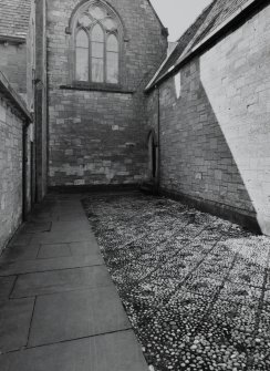View of cobbled court outside N cloister door from E