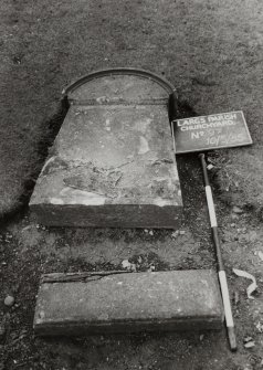 View of collapsed headstone with semi circular feature.  
Insc: "R . M ."  
Largs Parish Churchyard No 97.


