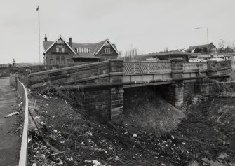 Context view from E, with road bridge over railway in forebround, showing that the line has been blocked