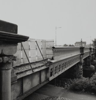 Oblique view from NW, showing portion of bridge with missing cast-iron parapet and cladding