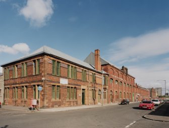 General view from SW of SW corner of works, showing elevations onto Norman Street (left) and French Street (right).  The view also shows the coloured enamel bricks decorating the office building occupying the SW corner of the works