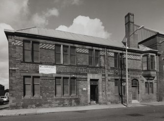 View from SSW of ornate brickwork comprising the elevation of the office building at the SW corner of works, which includes brown, blue and dark blue enamelled bricks within a fine facade of red facing brick with red sandstone insertions (including springers for arches above windows)