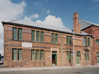 View from SSW of ornate brickwork comprising the elevation of the office building at the SW corner of works, which includes brown, blue and dark blue enamelled bricks within a fine facade of red facing brick with red sandstone insertions (including springers for arches above windows)