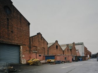 View from WSW along S side of former plumbers' shops with former engine works beyond.