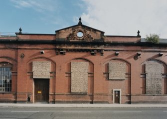 View from NW of central pedimented portion of works, showing three arcaded red-facing-brick bays and ornate red sandstone pediment