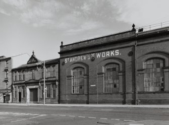 View from W of NE end of SW (main) facade of works, showing red-facing-brick arcaded bays, and to left, the red sandstone office building.  This part of the works is currently occupied by Glasgow City Council's Printing Works