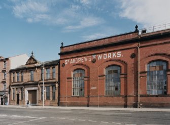 View from W of NE end of SW (main) facade of works, showing red-facing-brick arcaded bays, and to left, the red sandstone office building.  This part of the works is currently occupied by Glasgow City Council's Printing Works