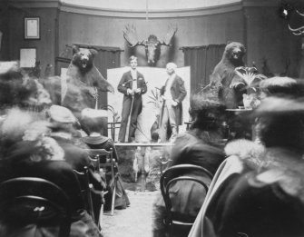 Interior. Performance with two gentlemen beside two stuffed bears.