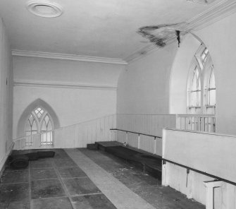 Interior.
View from W of S gallery showing remains of pews, dado panelling, Gothic windows and ceiling ventilation hole.