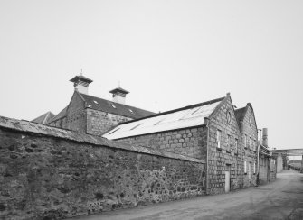 View from NW of main production block of distillery, showing ornate gables of the Tun Room and Mash House, with Malt Bins and Kilns in background, and Still House (R)