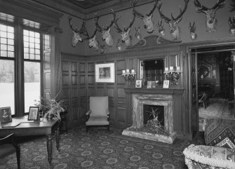 Interior. Ground floor view of sitting room from East looking towards the dining room showing the fireplace, original furnishings, fittings and stags heads