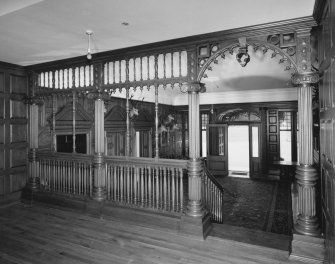 Interior. Ground floor view of entrance hall from North from the first landing of the staircase through the timber screen to the open front door