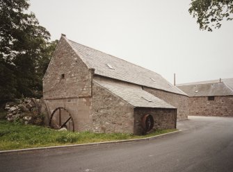 Exterior view of mill from SW, showing gable with undershot (start & awe) water-wheel and concrete lade