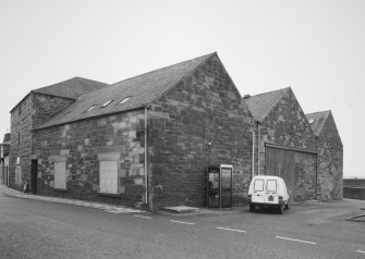 General view from NW, showing old granary (left), and three bays of fish processing works (right)