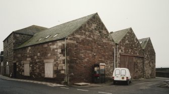 General view from NW, showing old granary (left), and three bays of fish processing works (right)