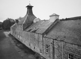 Elevated view from N along NE side of main range of distillery's production buildings, showing Mash House, Malt Store, former maltings Kiln, NE end of Maltings range, and second maltings Kiln