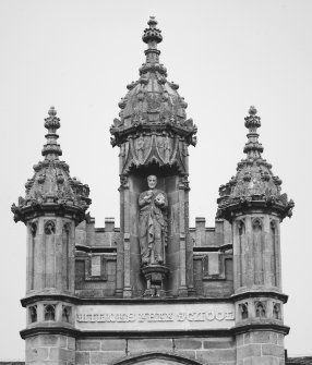 Detail of crocketed pinnacles and statue in niche of tower on N face.