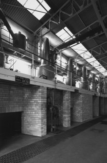 View at ground level from NE within Still House, showing row of 8 stills, all but 2 of which were built by A.Forsyth of Rothes. The stills, which are coal fired, are arranged with wash and spirit stills in pairs, the latter being the smaller stills (with the more rounded necks).