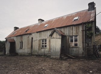 General View of former farm house from South showing tin sheeted roof and wall