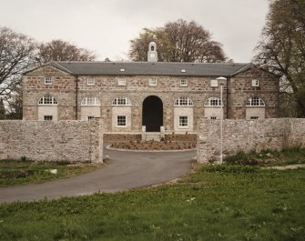 View of front of stable block and yard wall from West