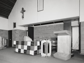 Interior. Detail of lecturn, font and communion table with cloth covering.