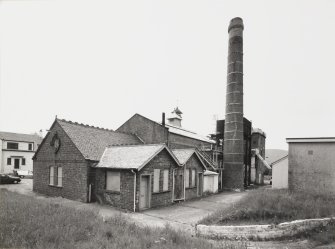 General view from NE of Spirit Store, Still House and Tun Room (with watch towers), and boilerhouse chimney.