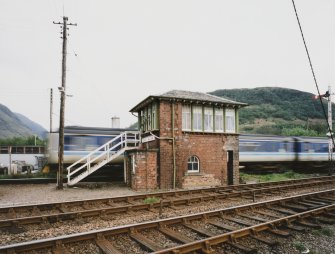 Fort William, Inverlochy, Signal Box
View from N across tracks of signal box, with sprinter train passing in background.  The tracks in the foreground lead to Mallaig, and those behind the signal box to Glasgow