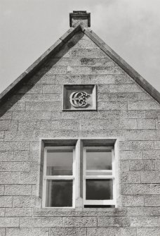 Top of gable, double window with carved panel containing monogram above, detail
