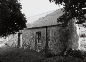 View from SW of front elevation showing harled rubble walls and corrugated iron roof.