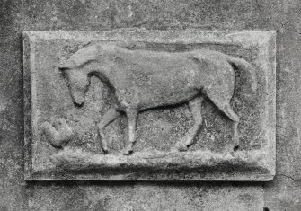 E courtyard range, arched opening, sculpted panel depicting horse and chicken, detail