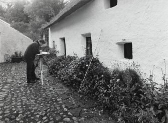 View of cobbled yard from N with RCAHMS staff member Mr J Borland surveying the building