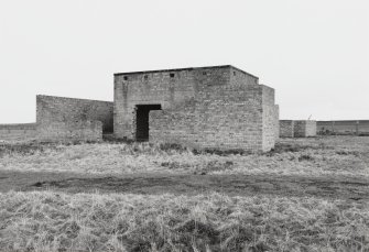 fearn Airfield, Loans of Tullich accommodation camp.  View from NW of main engine house with balst walls.  A secondary/emergency engine or generator house and the perimeter fence are visible in the background.