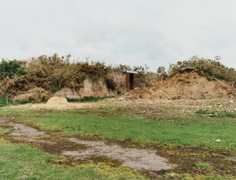 Fearn Airfield on N side of airfield.  View of remains of the protective earthworks with brick built bomb store building in the centre.