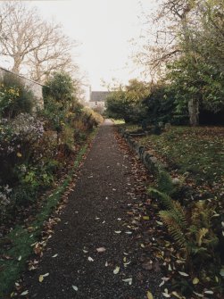 View of gravel path in front of plant border leading to garden front of Geanies house