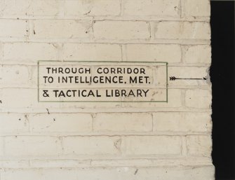 Tain Airfield Operations Block, upper main corridor, detail of sign painted on wall 'Through corridor to Intelligence, Met. & Tactical Library'.