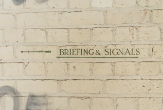 Tain Airfield Operations Block, upper main corridor, detail of sign to 'Briefing & Signals'.