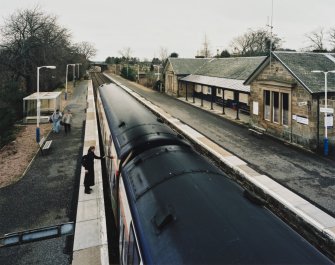 View from NW (from footbridge) showing station building and platforms, with southbound train in station