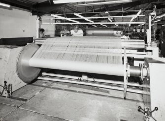 New Loom Flat:  View of Re-beaming Machine being operated by Colin Dent, who is using a portable knotting machine