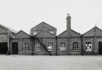 View from S of S side of central block of works, showing red Brora brick construction, and gabled bays of former railway engineering works (now the 'Warehouse' building 4), with Cloth Finishing (upper floor of building 5) in background. [the building numbers in brackets refer to the itemised plan, D33088]